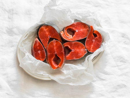 Pieces of fresh raw salmon on paper on a light background, top viewの写真素材