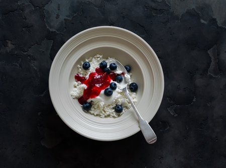 Delicious healthy breakfast - cottage cheese with Greek yogurt, raspberry sauce and blueberries on a...
