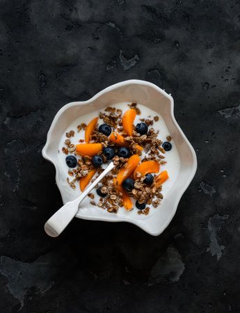 Delicious healthy breakfast - Greek yogurt with granola, apricots and blueberries in a ceramic bowl...