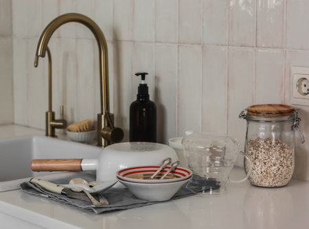 Washed dishes - bowls, saucepan, cutlery, glass coffee pot on a towel near the sink in the kitchen