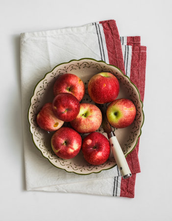 Fresh red apples in a bowl on a napkin on a white table, top viewの写真素材