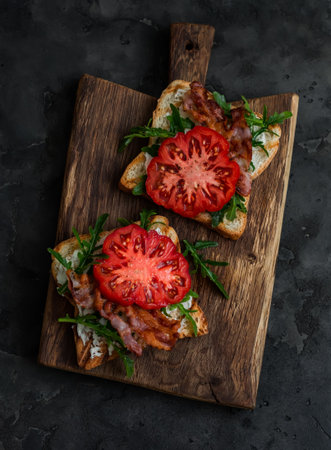 Grilled toasts with cheese, arugula, bacon and tomato - delicious appetizer, tapas, snack, breakfast...