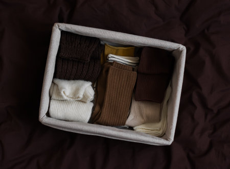 Cotton and wool socks in a box on a bed with a brown sheet