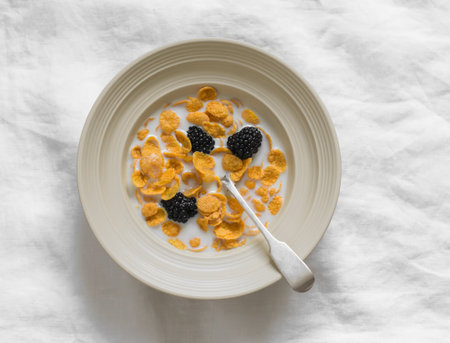 Delicious breakfast, snack - cornflakes with blackberries on a light background, top viewの写真素材