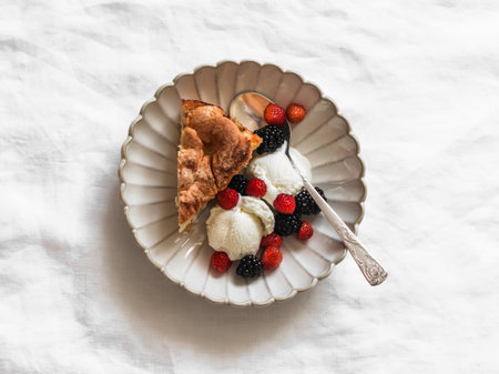 A piece of apple pie with ice cream and fresh berries on a light background, top viewの写真素材