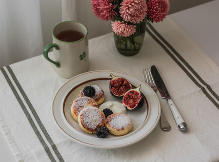 Breakfast, brunch - a cup of tea, coffee and syrniks with fresh figs, blackberries and Greek yogurt on the tableの写真素材