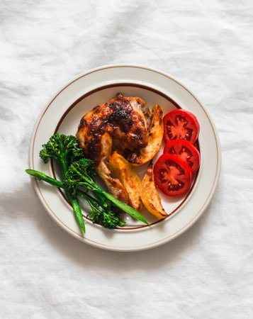 Delicious homemade lunch - baked chicken with potatoes, broccoli and tomatoes on a light background, top viewの写真素材