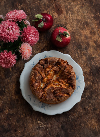 Apple cake with cinnamon, bouquet of asters, apples on a wooden table, top viewの写真素材