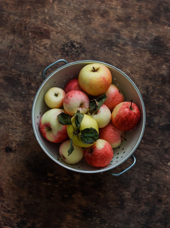 Ripe juicy apples in a metal colander on a wooden background, top viewの写真素材