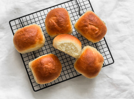 Homemade buns on a baking rack on a light background, top view
