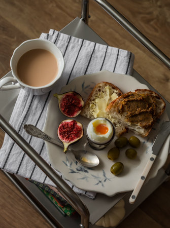 Delicious breakfast - boiled egg, toasts with liver paste and butter, olives on a metal tableの写真素材