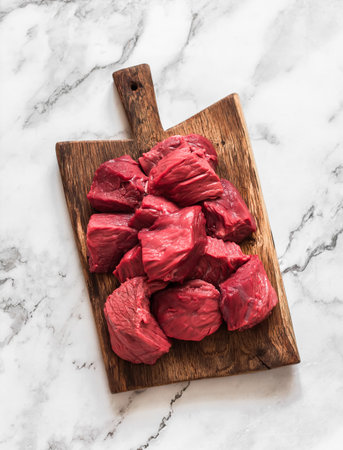 Fresh beef fillet cut into pieces on a rustic wooden board on a marble backgroundの写真素材