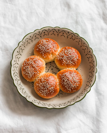 Sweet sesame buns in a baking dish on a light table, top viewの写真素材