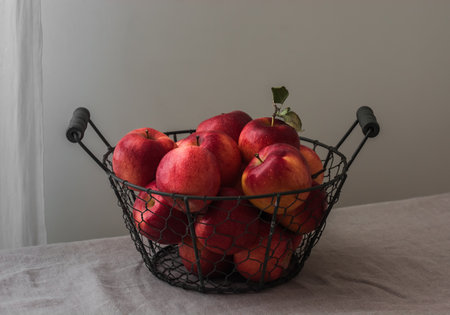Ripe red apples in a metal basket on the tableの写真素材