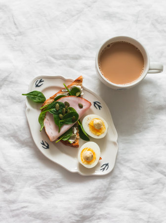Delicious grilled breakfast - bread toast with cream cheese, spinach, ham, pumpkin seeds, boiled egg...