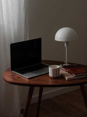 Laptop, desk lamp, notepad, glasses, a glass of coffee on a wooden table
