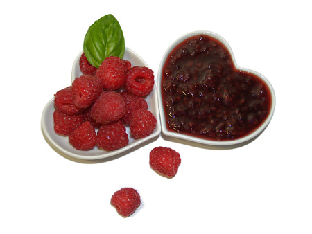 Raspberries and raspberry jam in heart white bowls