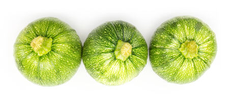 Three round zucchinis in a row isolated on whiteの写真素材
