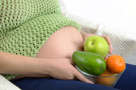 Pregnant woman with bowl of fruits and vegetablesの写真素材