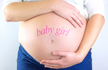 Pregnant woman belly with "baby girl" textの写真素材