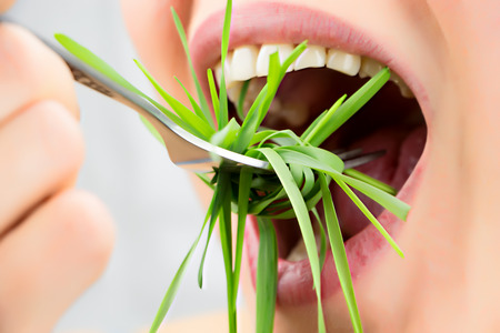 Open mouth with fork eating wheatgrass as spaghettiの写真素材