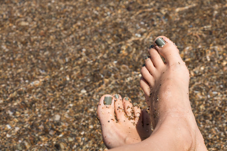 Wet female feet by water on sandの写真素材