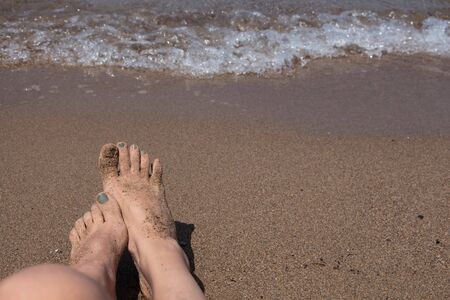 Wet female feet by water on sandの写真素材