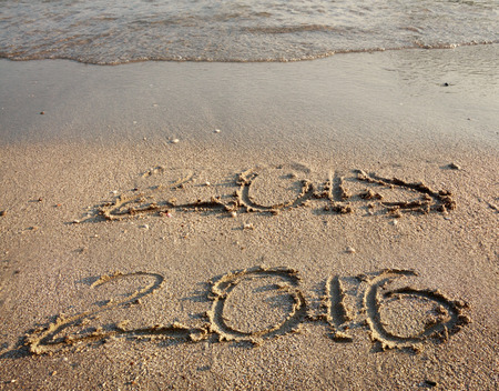 Sandy beach with hand drawn 2015 almost gone by waves and clear 2016