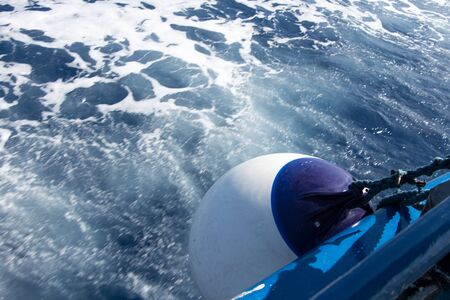 Seascape with water trail from boat with focus on white ball fender