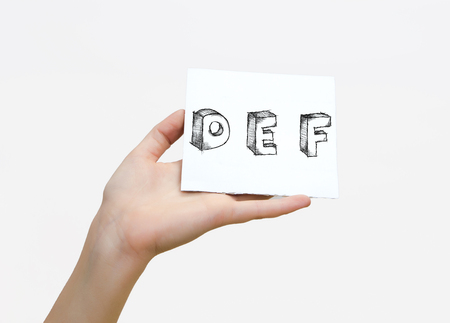 Hand holding a piece of paper with sketchy capital letters  D E F, isolated on white.の写真素材