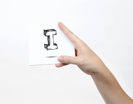 Hand holding a piece of paper with sketchy capital letter I, isolated on white.の写真素材