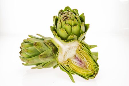 Fresh artichokes, one cut in half, isolated on white background.の写真素材