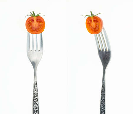 Cherry tomato cut in half on fork, front and side view, on white background.の写真素材