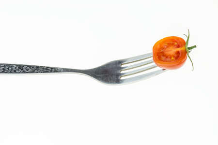 Cherry tomato cut in half on fork, on white background.の写真素材