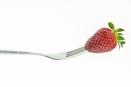 Fresh juicy strawberry on fork, on white background.の写真素材