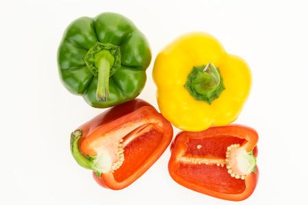 Fresh green, yellow and cut in two red bell peppers, isolated on white background.の写真素材