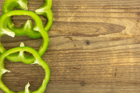 Fresh green bell pepper rings, on wooden surface.の写真素材