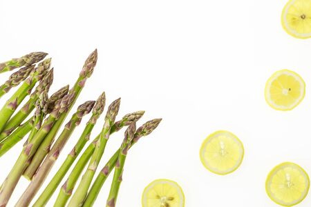 Bunch of asparagus spears and lemon slices, on white background with copy-spaceの写真素材