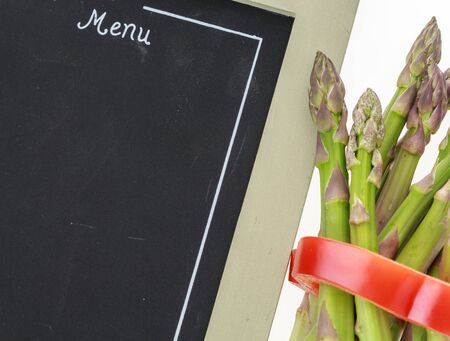 Bunch of asparagus tied with pepper ring and blank chalkboard menu closeupの写真素材