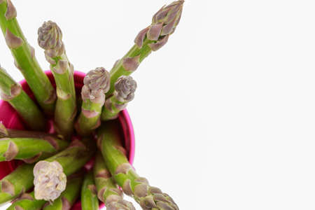 Bunch of asparagus in pink bucket, top view, on white background with copy-spaceの写真素材