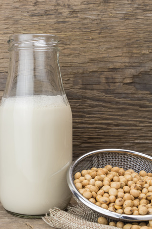 Soybeans and bottle of soy milk, on wooden background.の写真素材