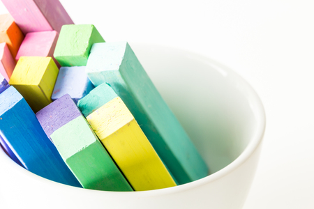 Bunch of square colorful pastel chalks in white bowl closeup, on white backgroundの写真素材