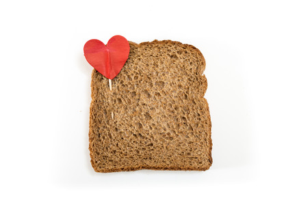Whole grain sandwich bread slice with heart pin, on white background.の写真素材