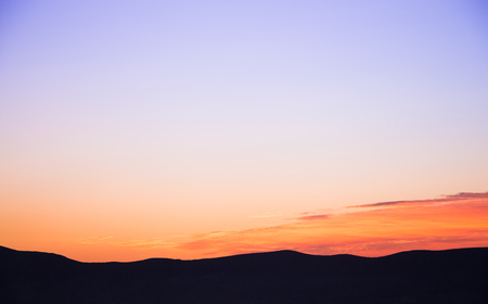 Beautiful vivid and colorful sunrise/sunset background with dark silhouettes of mountains.の写真素材