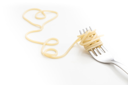 Plain cooked spaghetti pasta on fork with heart shape, on white background.の写真素材