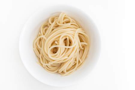 Plain cooked spaghetti pasta in white bowl, on white background.の写真素材