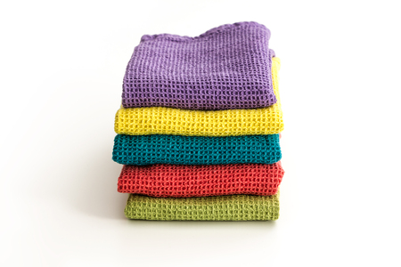 Stack of neatly folded colorful kitchen towels, on white background.の写真素材