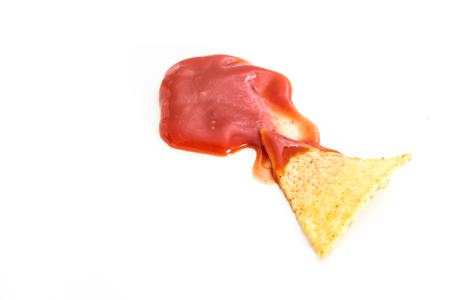 Crispy nacho chip in salsa, on white background.の写真素材