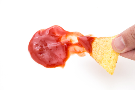 Crispy nacho chip in salsa, on white background.の写真素材