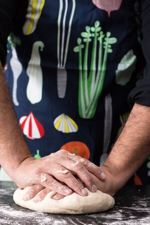 Male hands kneading dough, baking preparation closeup.の写真素材